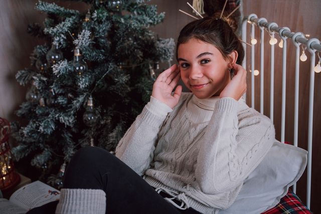 chica tocándose las orejas, de fondo un árbol de navidad