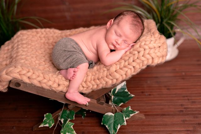 bebe con toalla marrón enredada en la cintura, durmiendo sobre silla plegable de madera