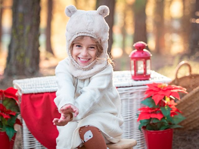 niña con capucha de orejas de oso frente a baúl de mimbre y flores de pascua