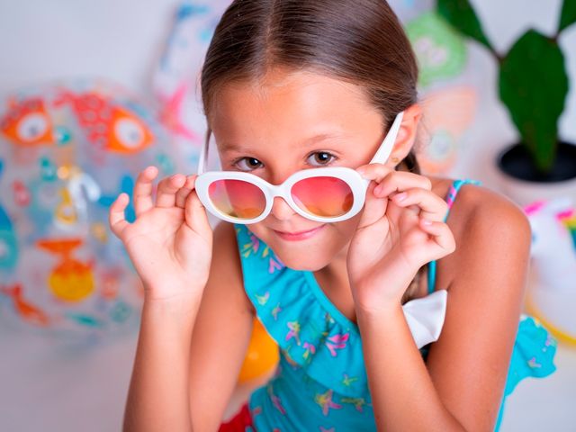 niña en ropa de verano poniéndose unas gafas de sol