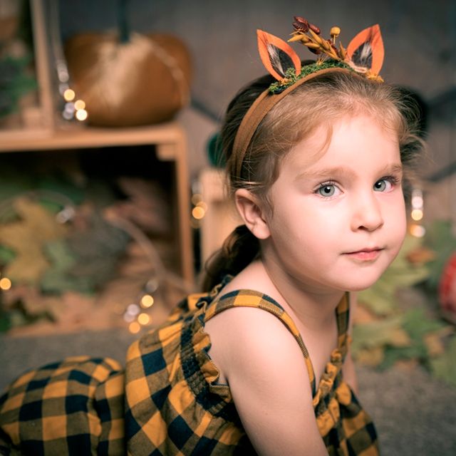 niña en vestido a cuadros amarillos y negros, con diadema de reno. de fondo decoración navideña