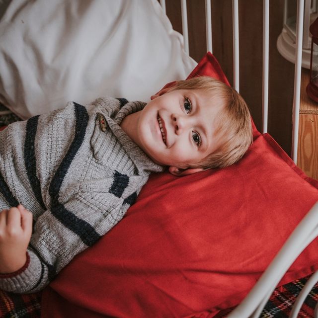 niño tumbado en una cama con sábanas rojas