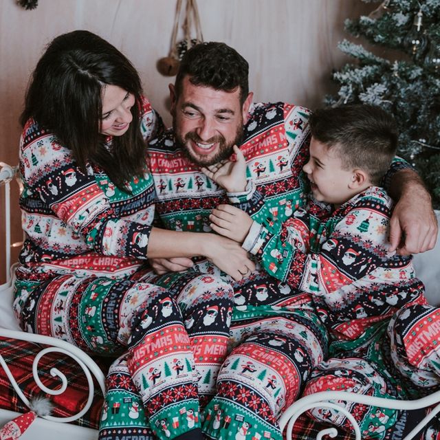 pareja con su hijo felices en una cama, con decoración navideña de fondo