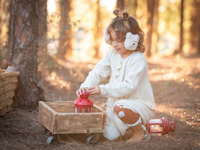 niña con vestido de lana y orejeras de oso, jugando con un farolillo rojo