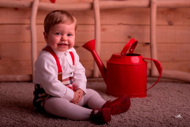 niño pequeño junto a regadera roja