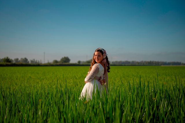 chica en vestido de comunión posando en un prado verde de hierba alta