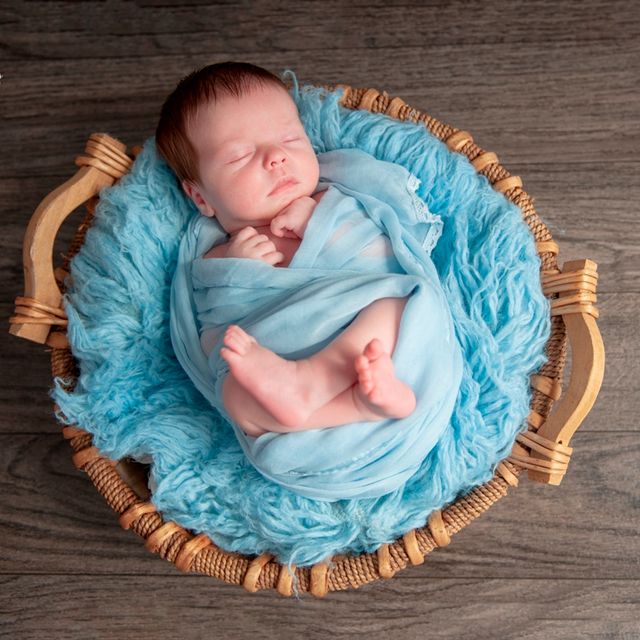 bebé dormido en una cesta de mimbre con sabanas celestes