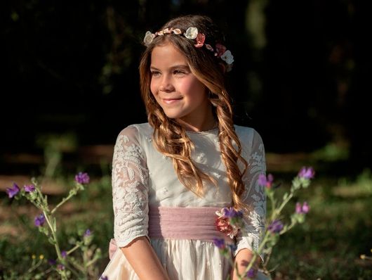 niña en vestido de comunión posando en el campo