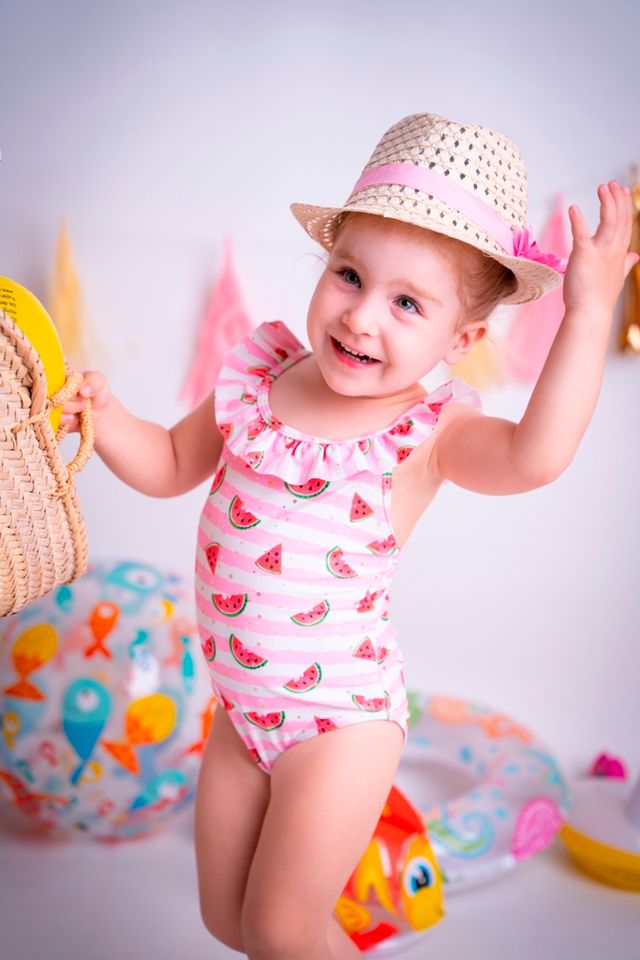 niña en bañador con sombrero de paja frente a decoración navideña