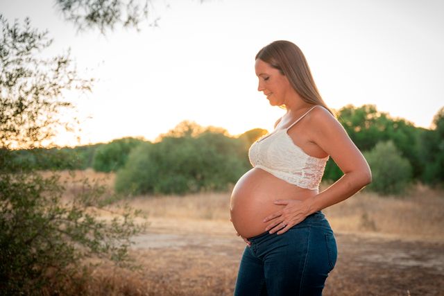 mujer embarazada posando en el campo al atardecer